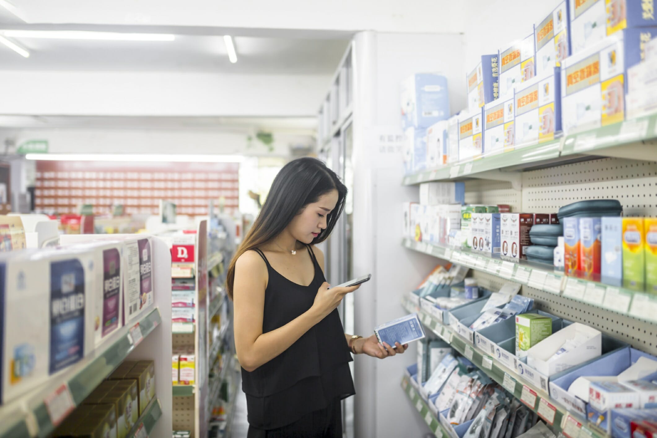 A young woman scans drugs with her mobile phone at a pharmacy