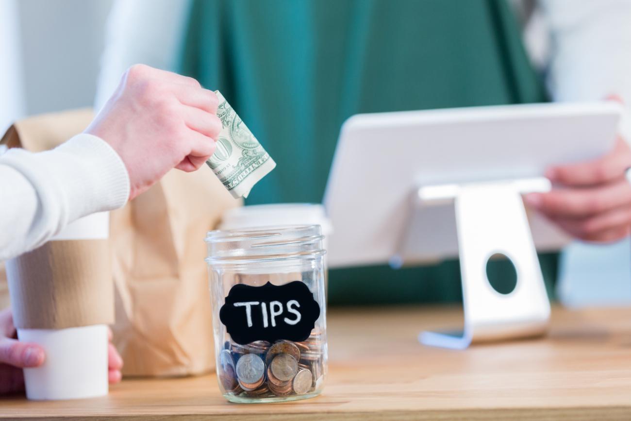 Image of coffee shop counter with tip jar and cashier screen